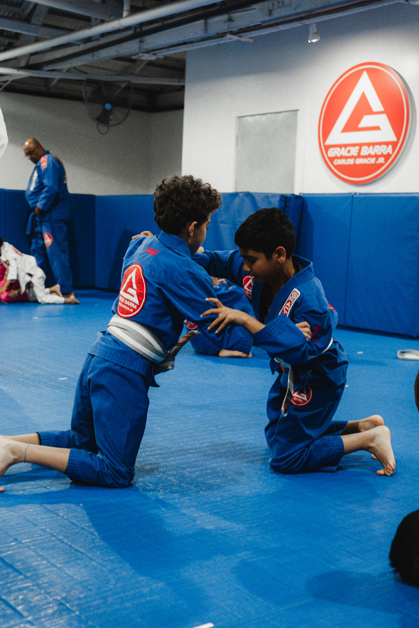 Group of martial arts practitioners gathering on academy mats following a disciplined group class.
